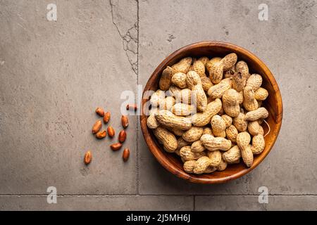 peanut nuts in a bowl on gray stone background top view with copy space. Healthy snack food. Stock Photo