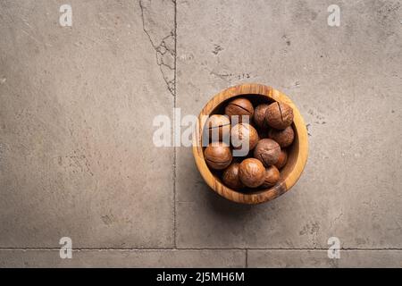 macadamia nuts in a bowl on gray stone background top view with copy space. Healthy snack food. Stock Photo