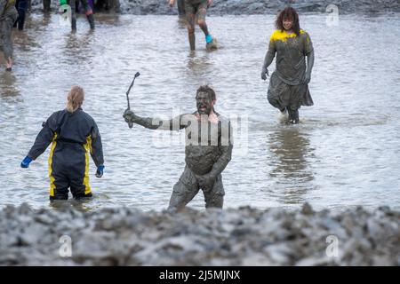 Competitors take part in the Maldon Mud Race in Maldon, Essex on April 24th 2022 as the race returns for the first time in two years. The Maldon Mud Race is an annual fun race held in spring (originally in the winter, now in late April or early May) at Promenade Park in Maldon, Essex, England, in which entrants compete to complete a 500 metres (550 yd) dash, in thick mud, over the bed of the River Blackwater. The race is organised by the Lions & Rotary clubs of Maldon and Maldon District Council which raises money for charity. Stock Photo