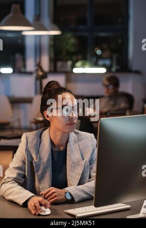 Serious focused young mixed race company manager in eyeglasses using modern computer and elaborating project strategy Stock Photo