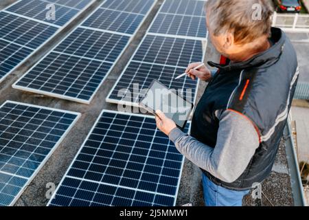 Close up of man technician using application. Checking solar panel setup.  Stock Photo