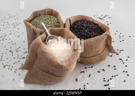 Three varieties of rice, green, white and black, in hessian bags Stock Photo