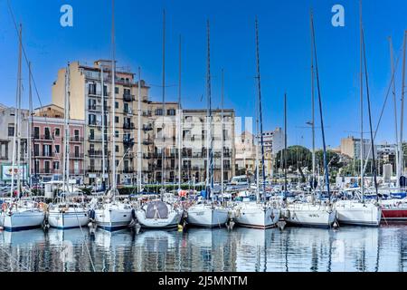 Yachts moored in Palermo harbour, Sicily, Italy, against the backdrop of the buildings along the seafront. Stock Photo