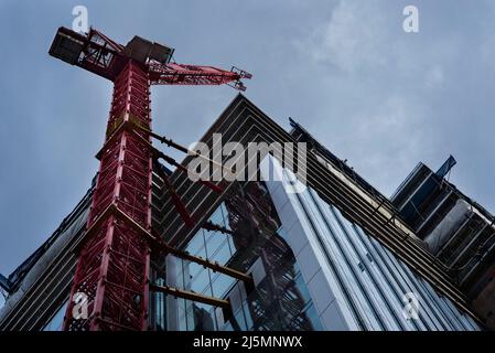 Tower crane attached to the tower block under construction. Building industry. Health and safety. Worksite safety. Stock Photo