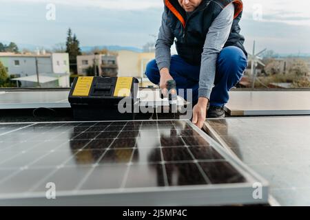 Engineer installing solar photovoltaic panel system using screwdriver. Alternative energy concept Stock Photo
