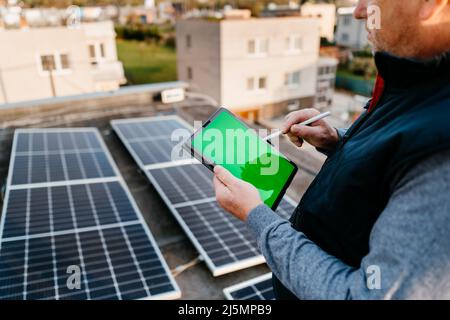 Worker installing solar energy systems. Using application. Tablet with green screen. Eco concept alternative energy Stock Photo