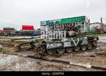 2022-04-09 Kyiv region, Ukraine. Damaged russian tank in front of the tractor warehouse on the E40 highway near Kyiv. War in Ukraine Stock Photo