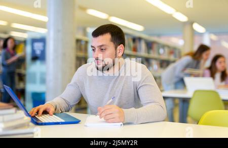 Focused man working on laptop at library Stock Photo