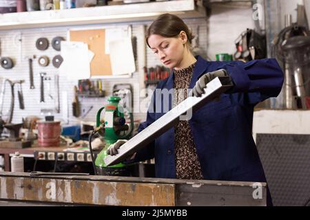Female worker controlling quality of metal parts Stock Photo
