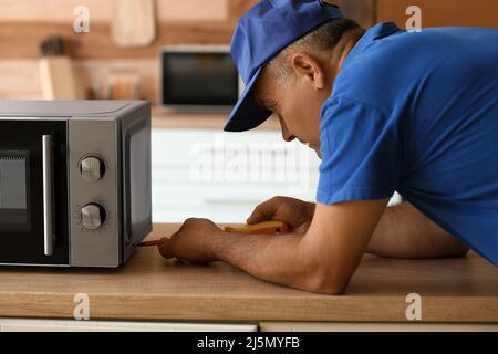 Male worker repairing microwave oven in kitchen Stock Photo