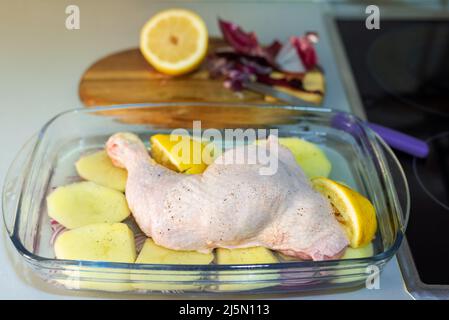 Tray on the kitchen counter with lemon chicken thigh, potatoes and red onion. Stock Photo