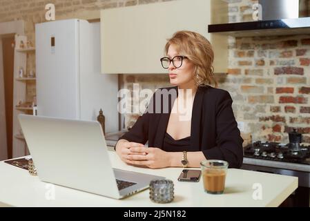 A girl in glasses gesturing while talking to her colleagues in a video call. Stock Photo