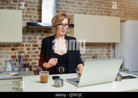A girl in glasses gesturing while talking to her colleagues in a video call. Stock Photo