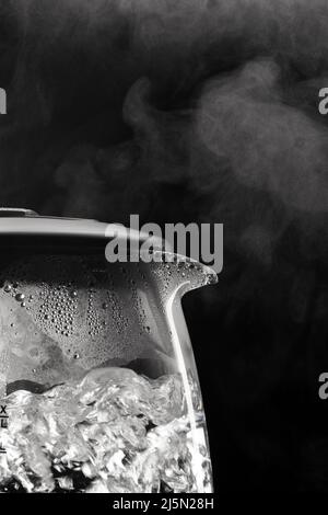 Close-up of steam and bubbles in an electric kettle against steam on a black background Stock Photo