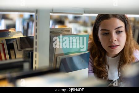 Portrait of woman choosing books at library Stock Photo