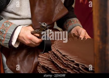 leather craftsman working in medieval market stall Stock Photo
