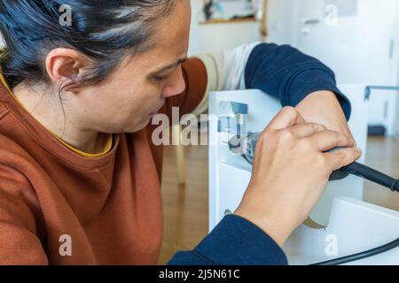 woman using mini drill and doing bricolage Stock Photo