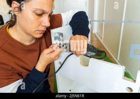 woman using mini drill and doing bricolage Stock Photo