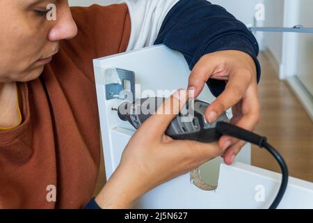 woman using mini drill and doing bricolage Stock Photo