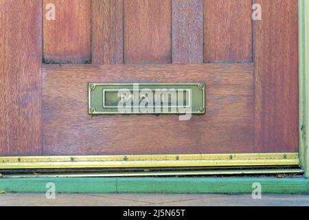 Letterbox on a wooden door at San Francisco, California. Metal letterbox with mail at the front at the bottom of the wooden door near the gold nailed Stock Photo