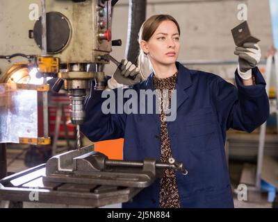 Woman drilling steel structures on drill press Stock Photo