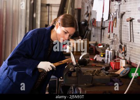 Young woman mechanic working with hand hammer Stock Photo
