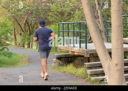 Back view of fat man jogging in park. Stock Photo