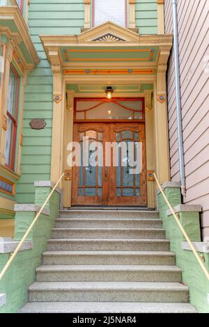 Townhouse entrance exterior with concrete doorsteps and large wooden double door. San Francisco residence in California with an exterior of wooden gre Stock Photo