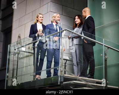 team of multiethnic business people standing talking chatting discussing in modern office building Stock Photo