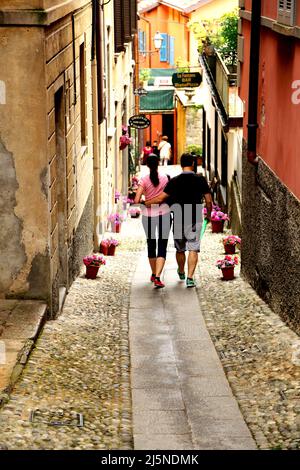 Couple walking down a cobbled street in Bellagio on the shores of Lake Como in northern Italy Stock Photo
