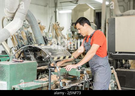 Master operating wood turning machine in workshop Stock Photo