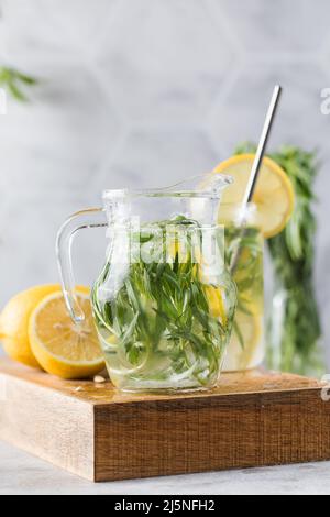 Refreshing homemade lemonade with tarragon and lemon in a jug. Summer drinks. Stock Photo