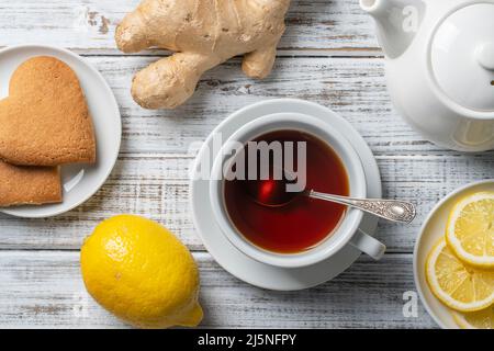White cup of tea with lemon and ginger on wooden table, close up, top view Stock Photo