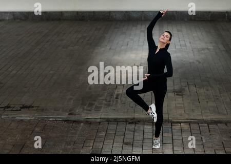 Young female dancer in black unitard enjoying performaning outdoors Stock Photo