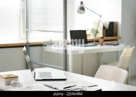 Modern portable computer, clipboard with documents on office table in open space office Stock Photo