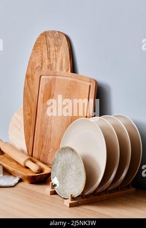 Set of wooden cutting boards and plates on a stand standing on table in kitchen Stock Photo