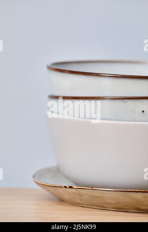 Close-up of stack of white ceramic bowls on plate isolated on blue background Stock Photo