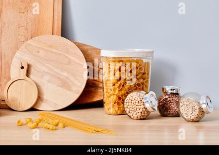 Image of pasta with spices in glass containers with wooden cutting boards on table on blue background Stock Photo