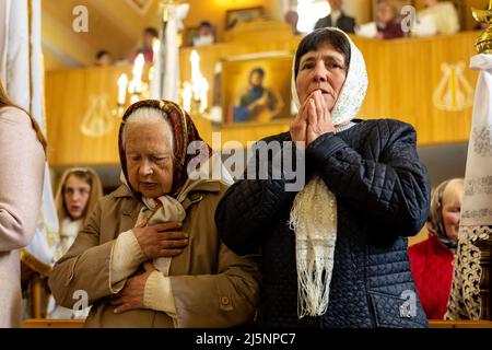 Ukrainian faithful pray during the Easter Sunday service, called Holy Pascha at Greek-Catholic church. Holy Pascha in Ukraine took place on Sunday morning instead of traditional midnight due to military curfew. As the Russian Federation invaded Ukraine nearly two months ago, the conflict forced more than 10 million Ukrainians to flee the war zones, both internally and externally. Nadyby village and its Greek Catholic church became a shelter for dozens of refugees from Kharkiv, Donesk and Zaporizhzhia Oblast. As Ukrainian faithful gather for orthodox Easter celebrations, local Christians and th Stock Photo