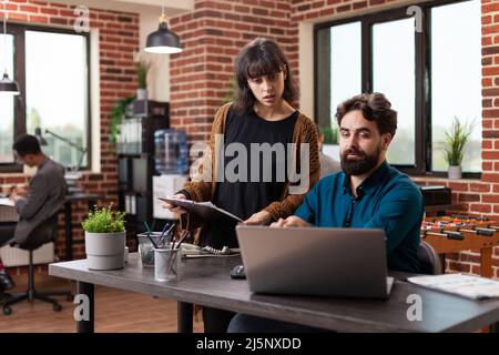 Executive managers analyzing papers with marketing statistics discussing company strategy while working at business collaboration in brick wall startup office. Businesspeople brainstorming ideas Stock Photo