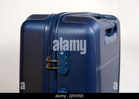 Combination lock and blocked zippers on a blue travel suitcase on a white background close-up. Travel safety. Stock Photo