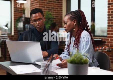 Accounting department employees reviewing financial documentation. Business company workers analyzing marketing documents and startup strategy expenses while in workspace. Stock Photo