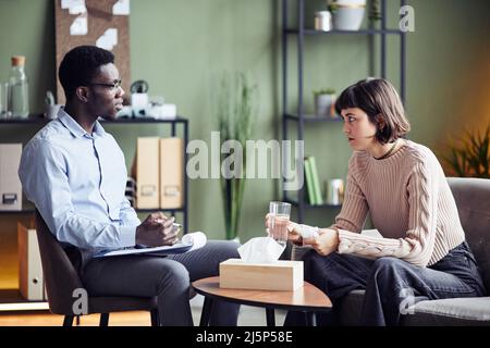 Psychologist taking notes during session with female patient in private consulting room Stock Photo