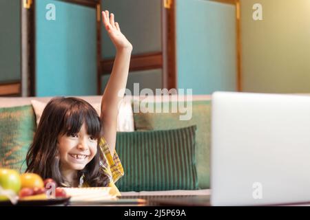 student studying online raise her hand to answer teacher's questions in online class. concept of live interactive, communication and response of learn Stock Photo
