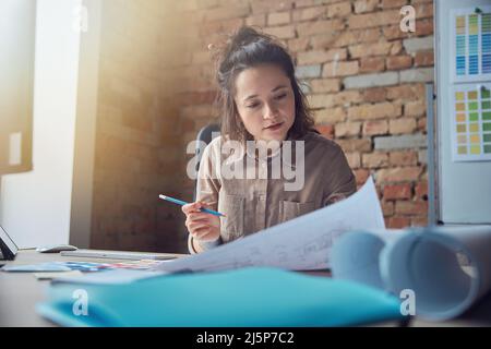 Busy female interior designer working with drawing, material sample in her office Stock Photo