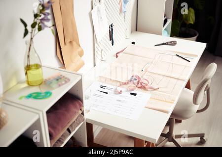 Sheet with fashion sketches, sewing pattern and measuring tape on desk of tailor or designer Stock Photo