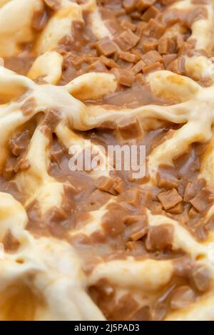 Macro photography of ice cream with caramel. A close-up view of a sweet dessert from above. Abstract food background. Vertical photo Stock Photo