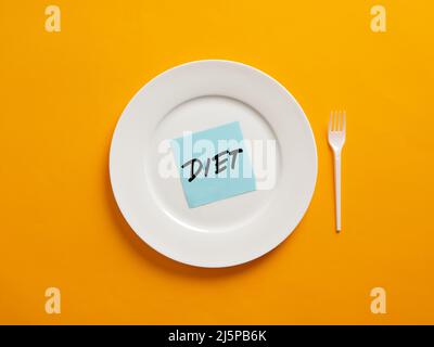 Notepaper with the word diet on a white plate with yellow background. Nutrition and diet concept. Stock Photo