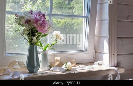 A bouquet of peonies on the windowsill Stock Photo