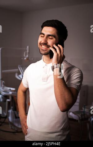 Doctor male, medical professional happy talking using a smartphone at hospital. close eyes. Stock Photo
